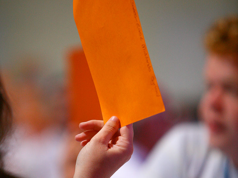 Hand holding an oranage piece of paper