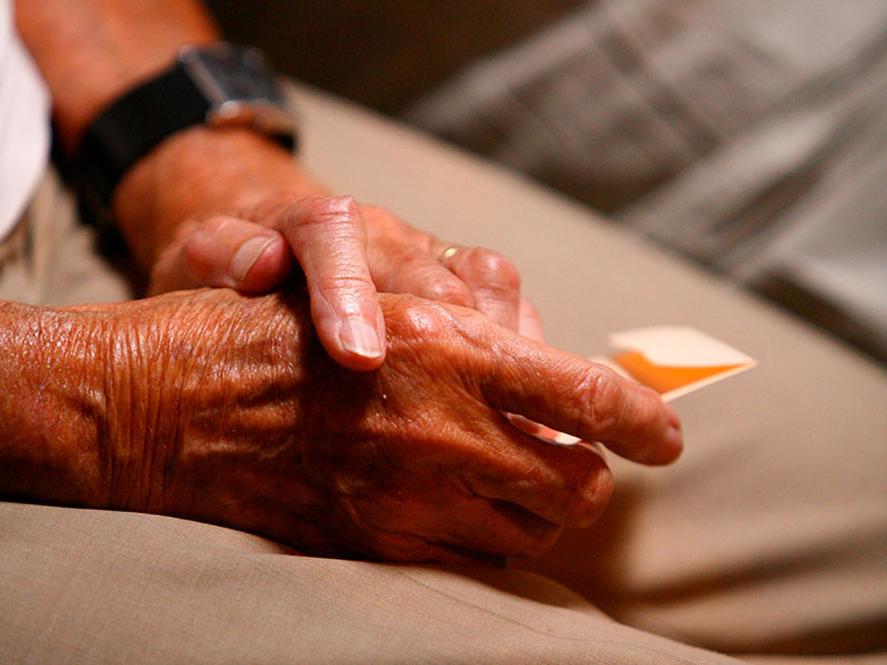A pair of hands holding a piece of paper and resting on a lap