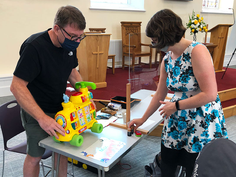 Two people setting up toys on a table