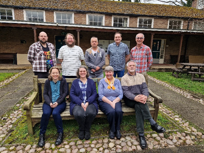 A group of happy people, training to be Assembly Accredited Lay Preachers, sitting and standing around a bench.